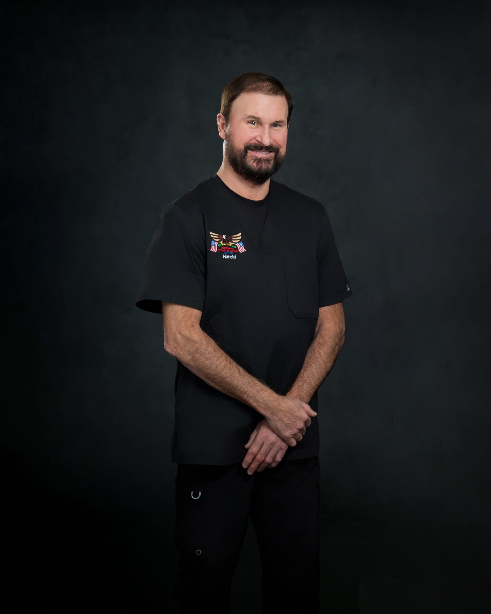 Man in Black T-Shirt Smiling Against Dark Background